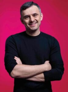 Gary Vaynerchuk with arms folded in black long sleeve in front of a red backdrop